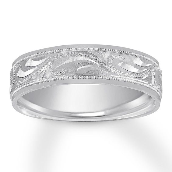 a wedding band with intricate engraving on the sides and an engraved design in white gold