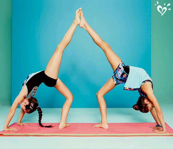 two women doing yoga poses on a pink mat