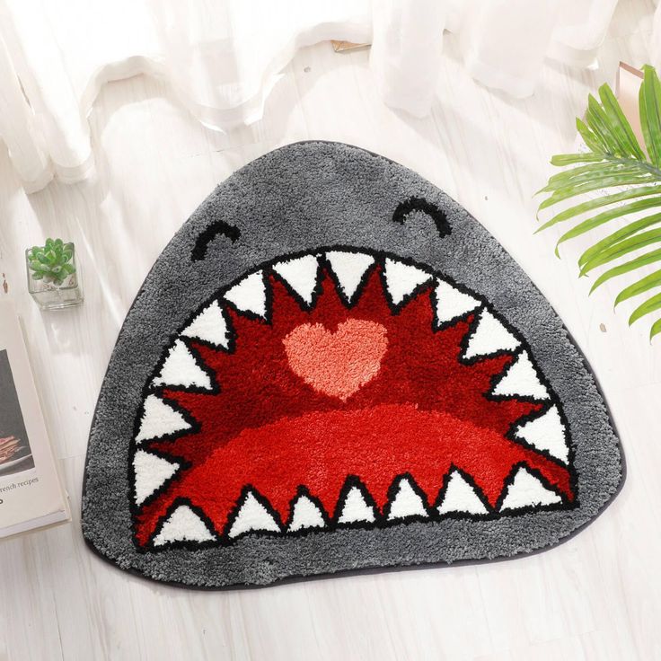 a rug with a shark's mouth on it next to a potted plant