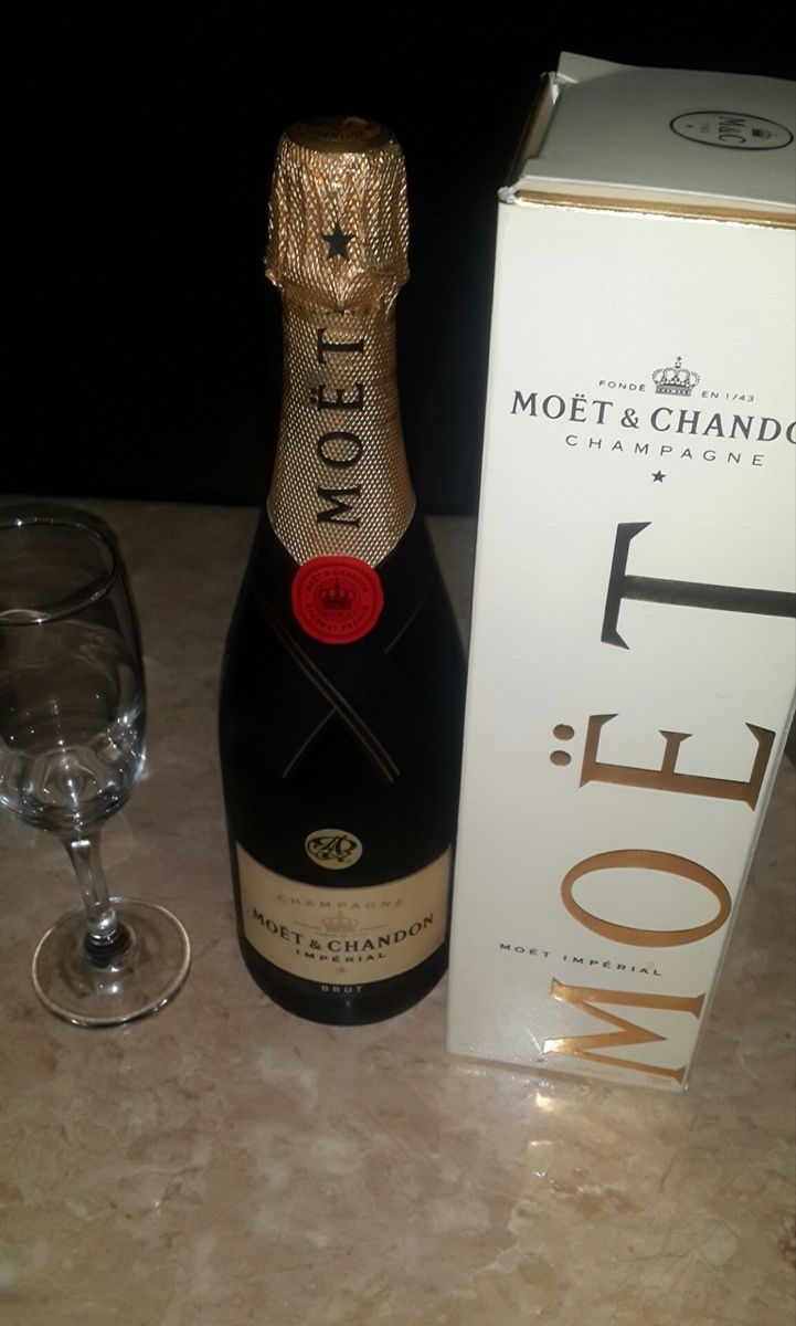 a bottle of champagne next to a wine glass on a table with a box in the background