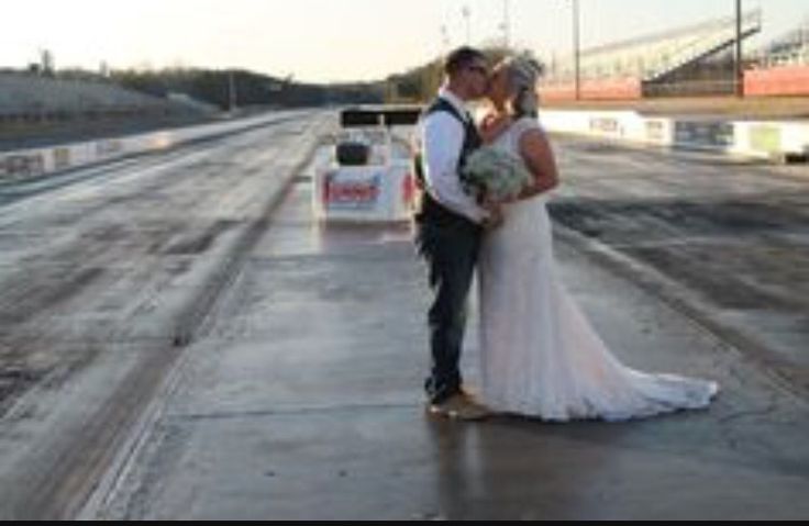 a bride and groom kissing on the side of an empty race track