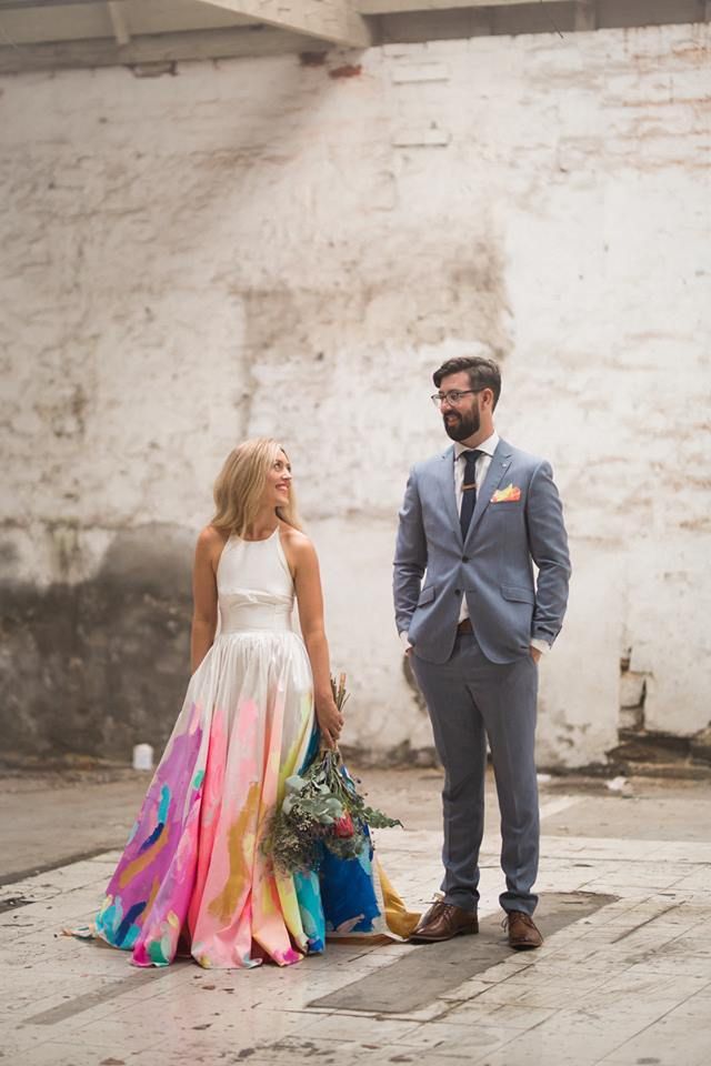 a man and woman standing next to each other in front of a white brick wall