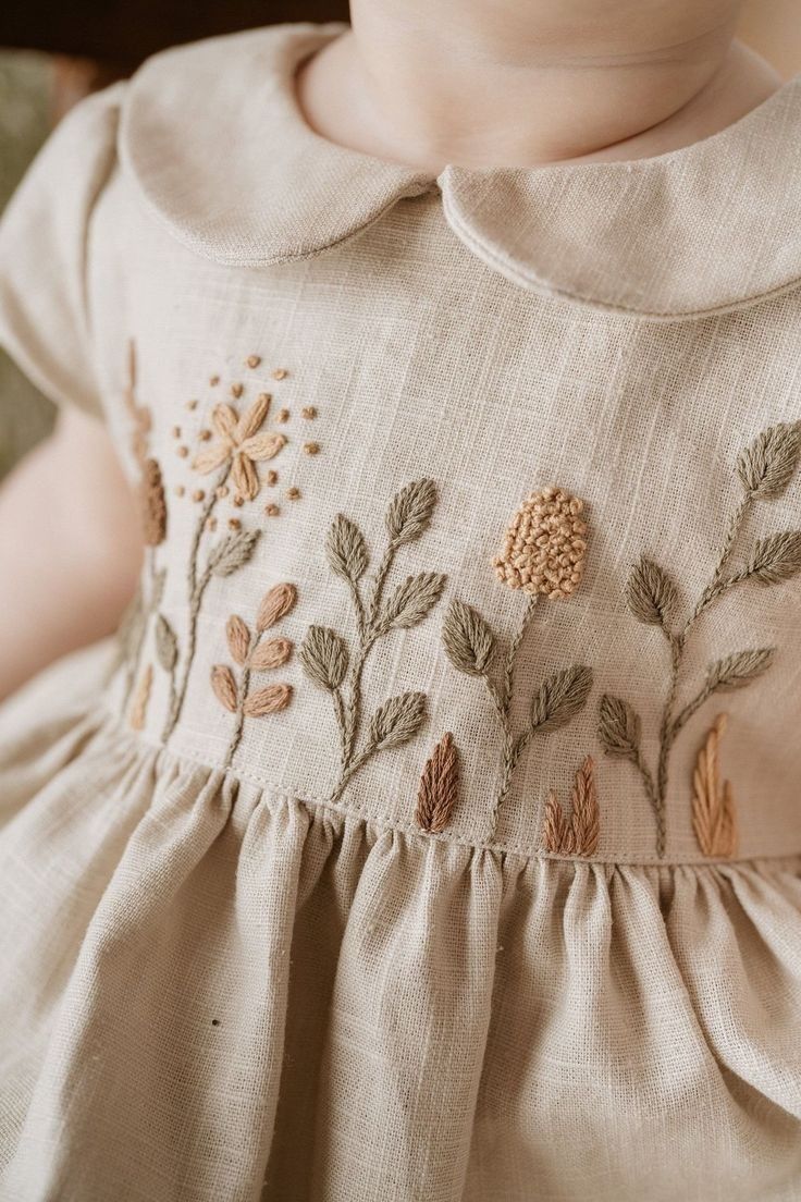 a close up of a child's dress with flowers and leaves on the chest