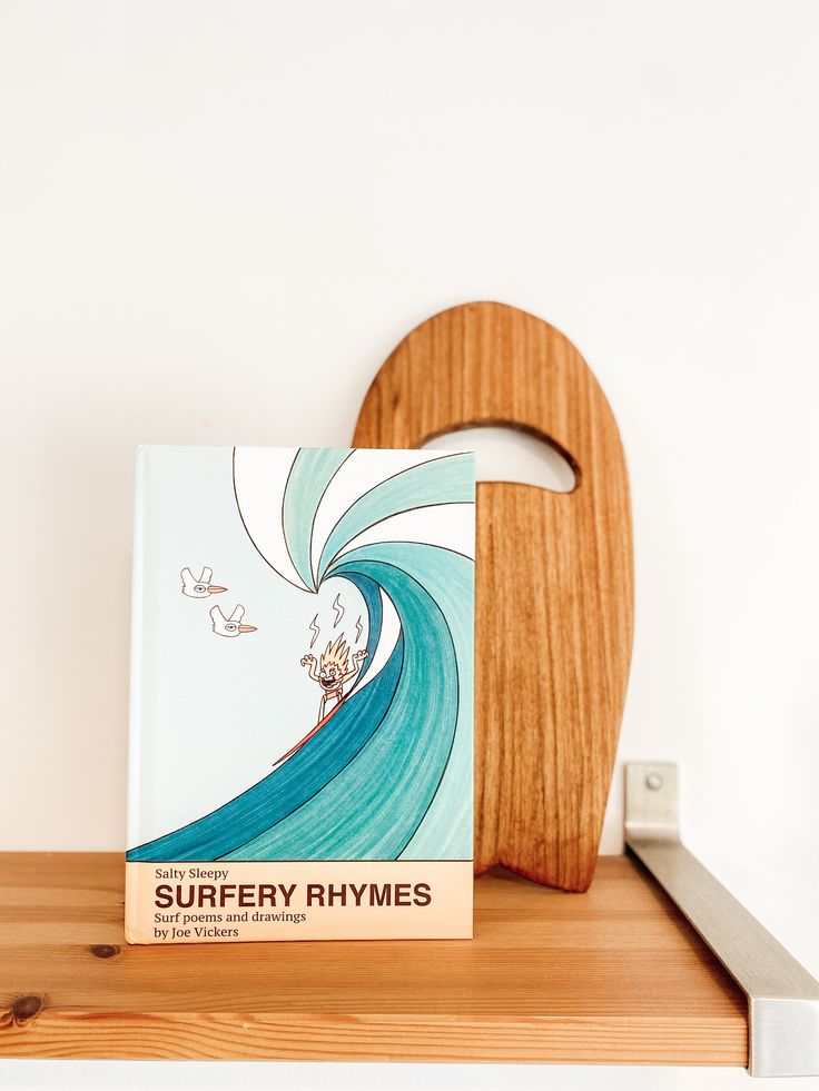 a book sitting on top of a wooden shelf next to a heart shaped cutting board