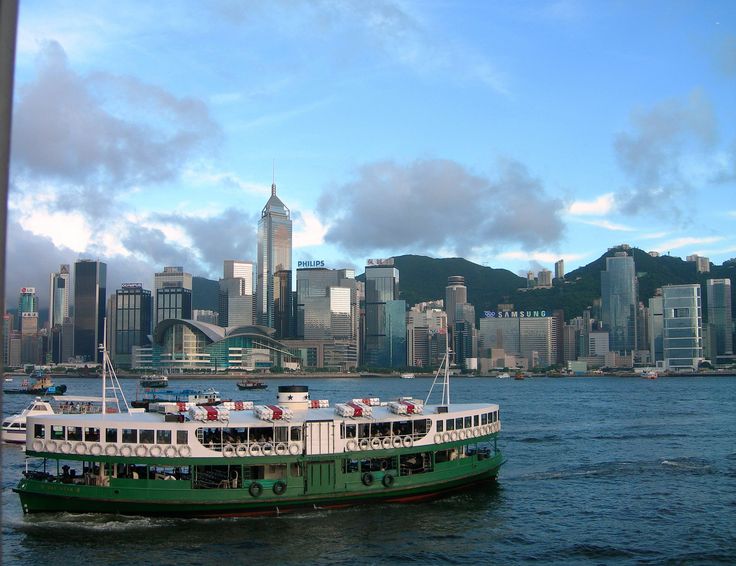 a green and white ferry boat in front of a cityscape on the water