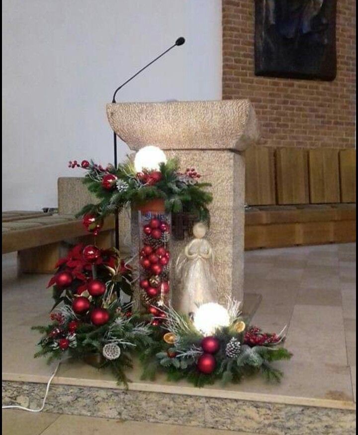 a statue is decorated with christmas wreaths and balls in front of a microphone on a stage