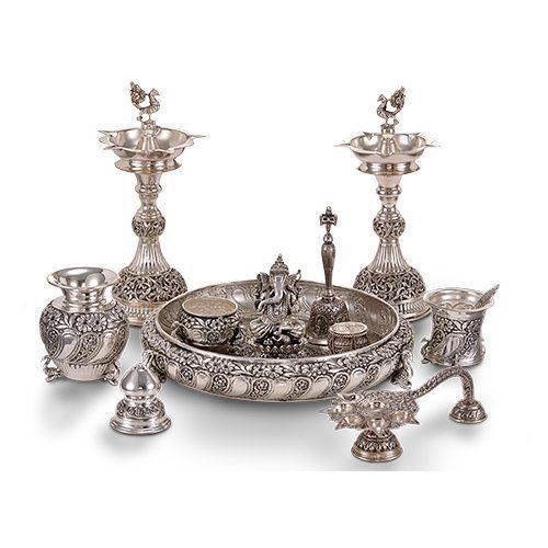 an assortment of silver items including candles and bowls on a white surface with one candle holder in the middle