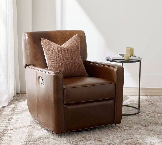 a brown leather chair sitting on top of a rug next to a table with a candle