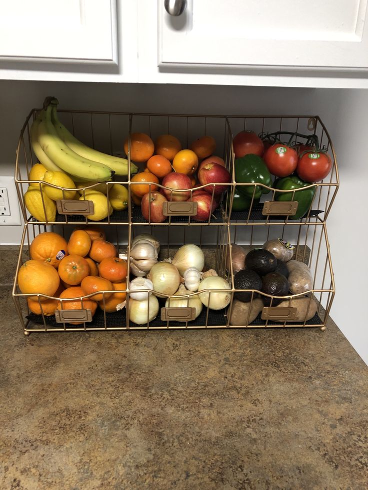 two metal baskets filled with different types of fruits and vegetables next to each other on top of a kitchen counter