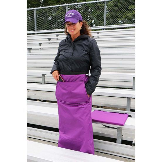 a woman standing in front of some bleachers wearing an apron and purple hat