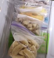 bananas are packed in plastic bags on the inside of an open refrigerator