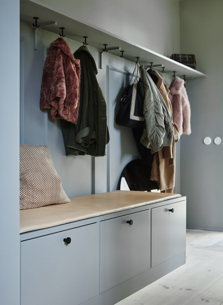 a coat rack with several coats hanging on it's sides and two benches below