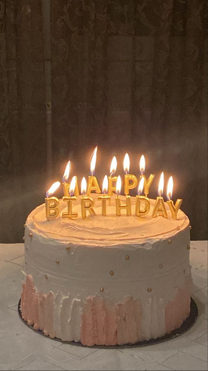 a birthday cake with white frosting and lit candles