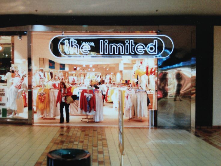 a store front with the words the limited on it's glass display window and people walking by