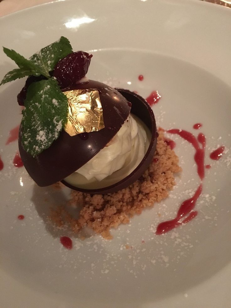 a white plate topped with an ice cream sundae covered in chocolate and strawberries