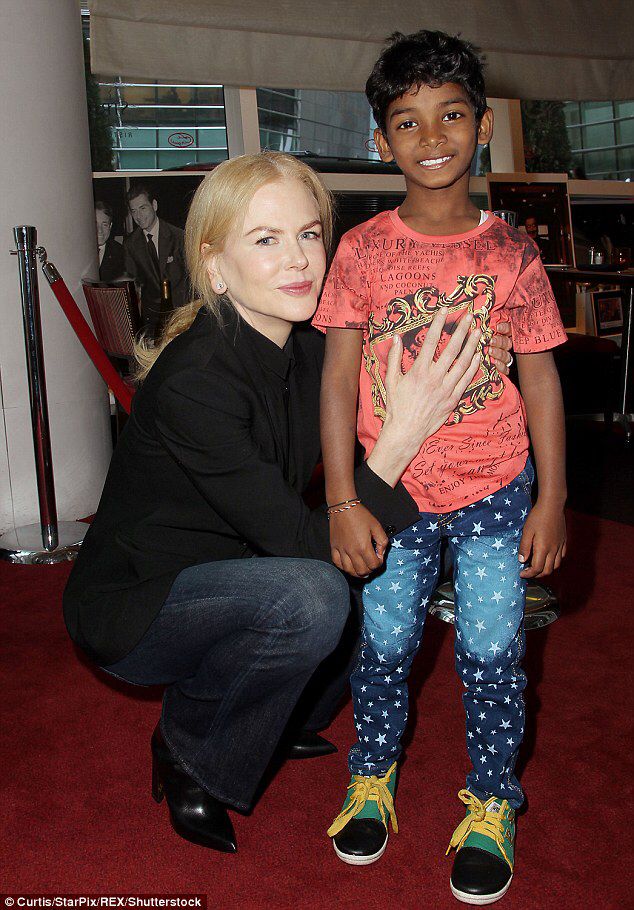 a woman kneeling down next to a little boy on a red carpet in front of a window