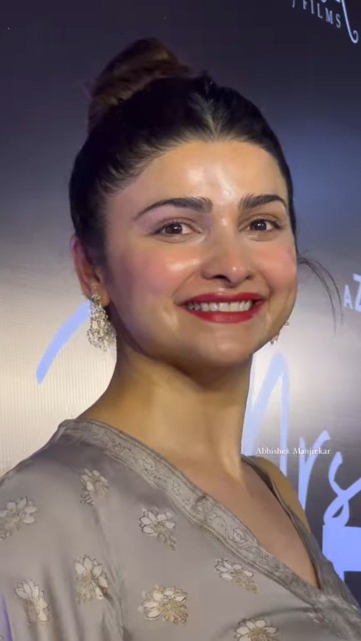 a woman smiling at the camera in front of a sign