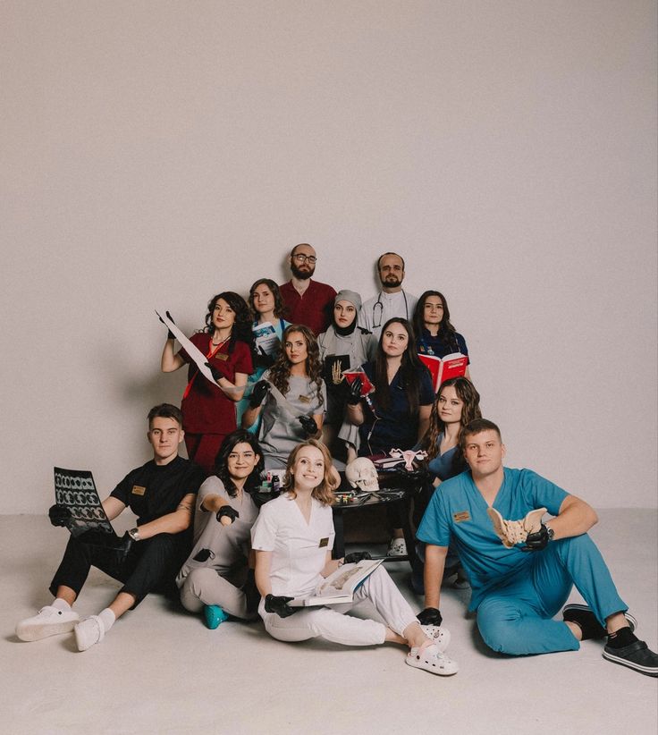 a group of people sitting and standing in front of a white wall posing for a photo