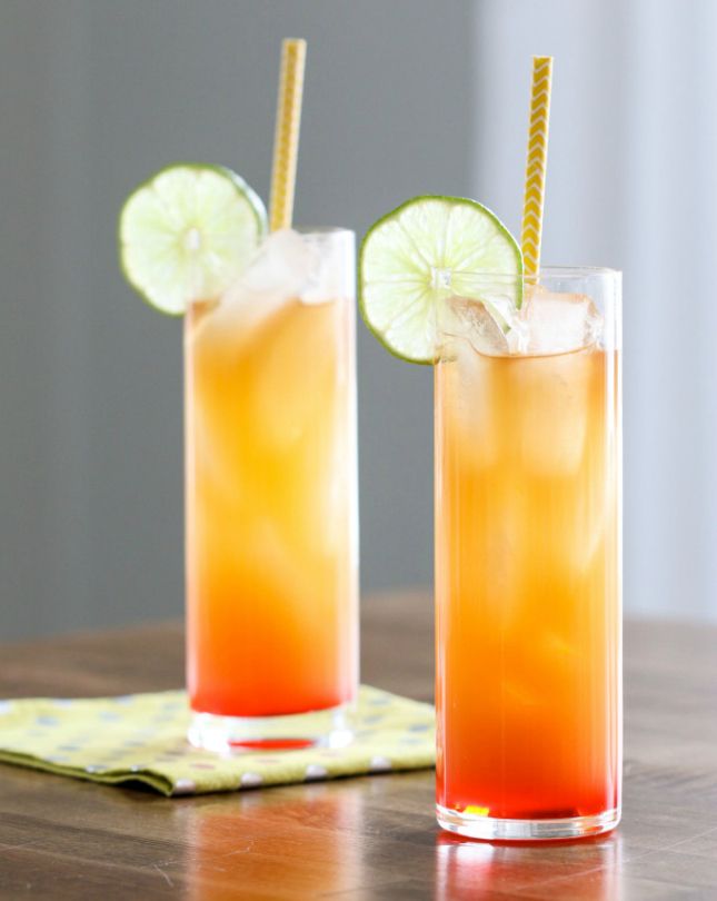 two glasses filled with drinks sitting on top of a wooden table