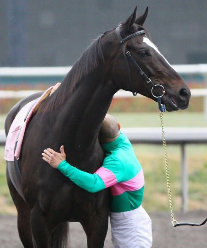 a man is hugging a horse on the track