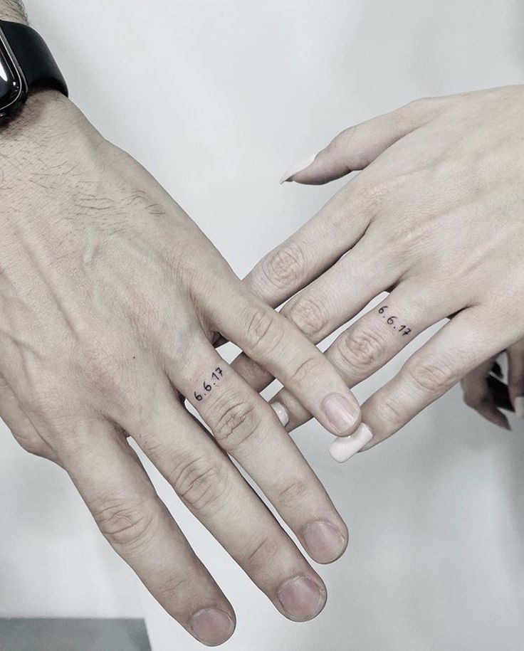 two people holding each other's hands with tattoos on their fingers and one is wearing a watch