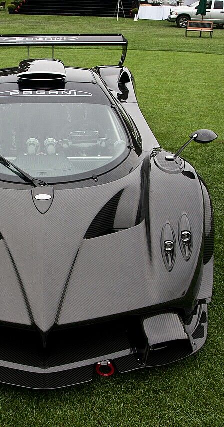 a grey sports car parked on top of a lush green field