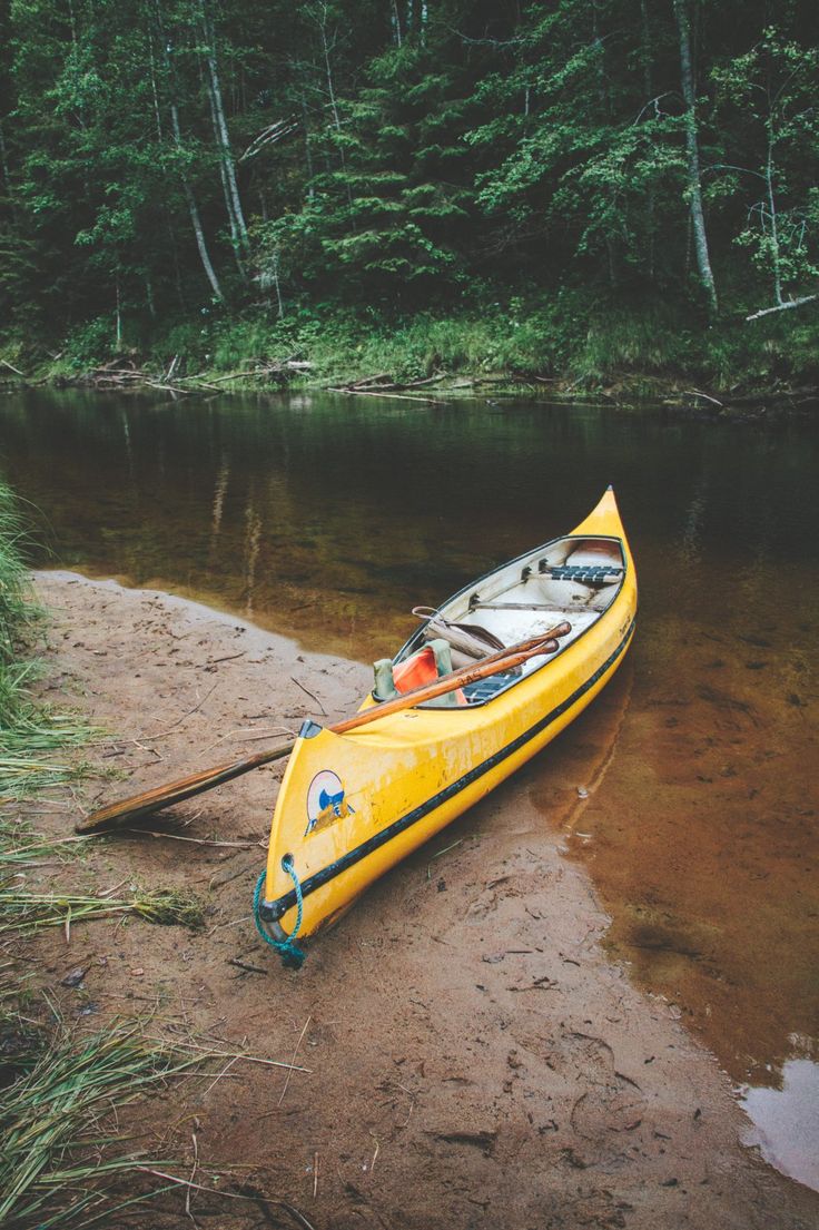 a yellow kayak sitting on the shore of a river