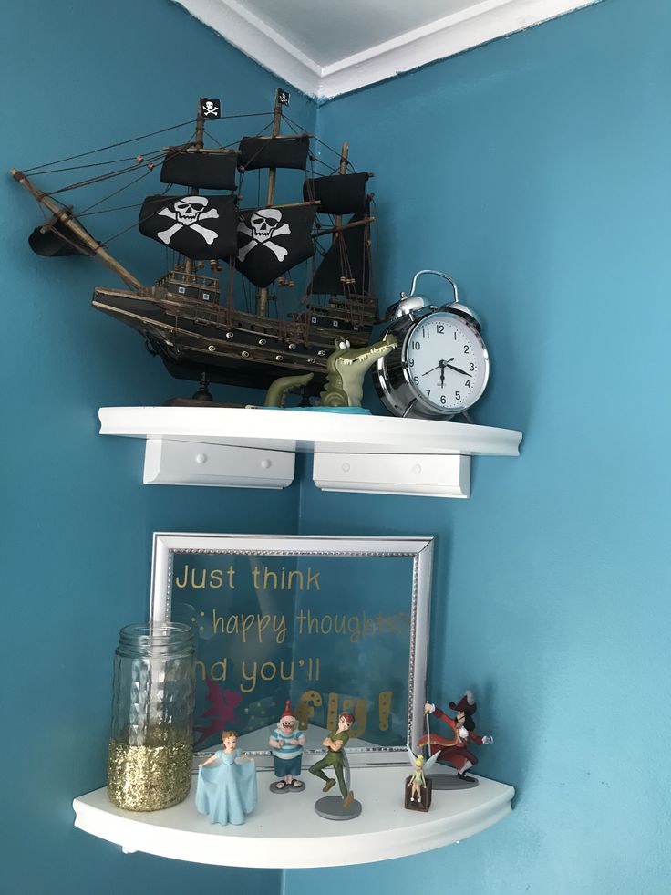 a shelf with a clock, pirate ship and other items on it in a blue room