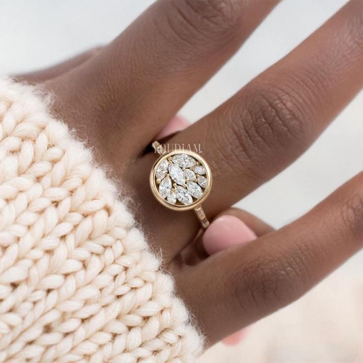 a woman's hand with a ring on it and a sweater in the background