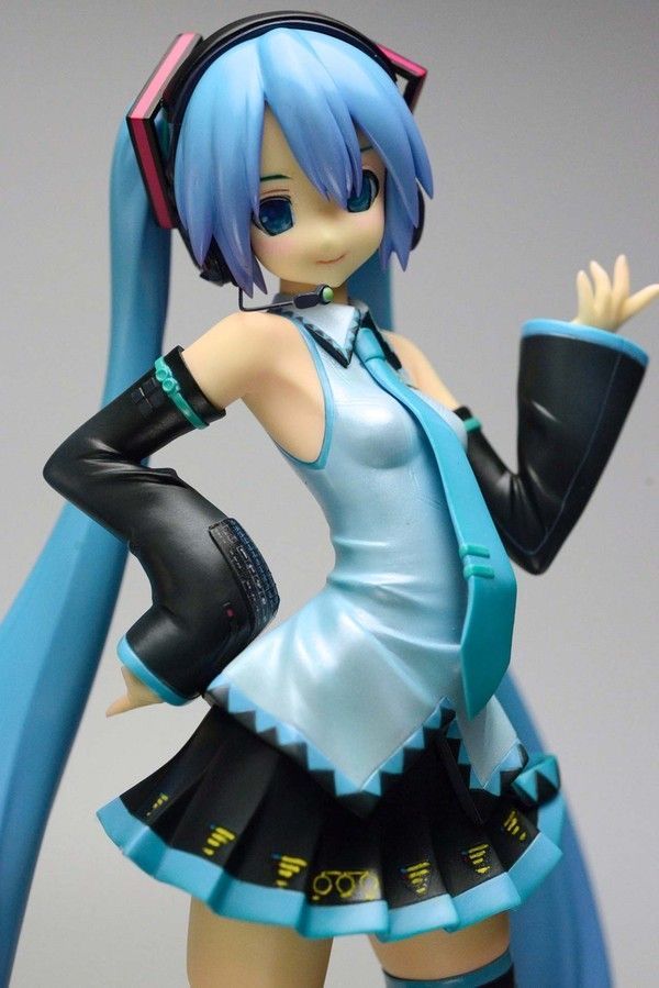 a figurine with blue hair and black boots is posed in front of a gray background