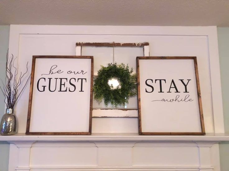 two framed signs that say be our guest, stay awhile and have a wreath on top