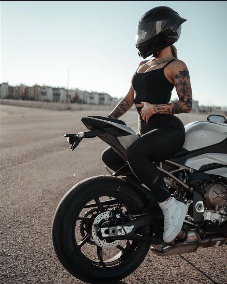 a woman sitting on top of a motorcycle in the middle of an empty road,