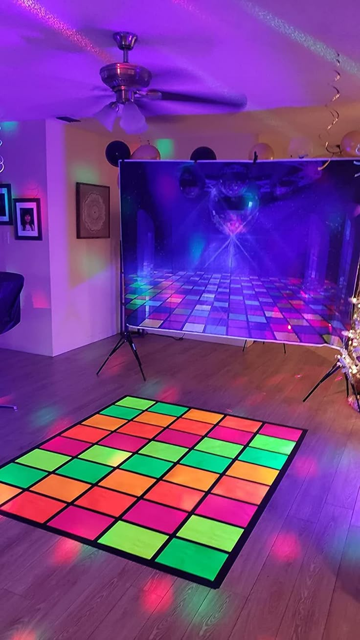 a brightly lit dance floor in front of a large screen with colorful lights on it