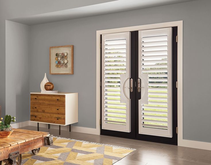 a living room with white shutters and wooden furniture