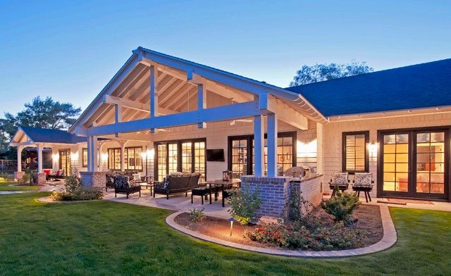 an outdoor living area at dusk with patio and dining table in the foreground, surrounded by grass