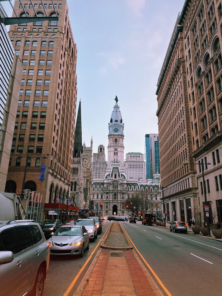 a city street with cars parked on both sides and tall buildings in the back ground