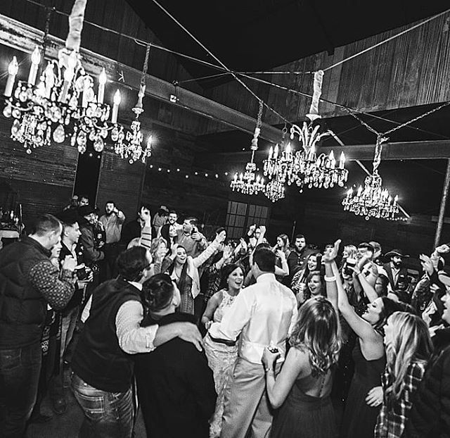 a group of people standing around each other in a room with chandeliers hanging from the ceiling