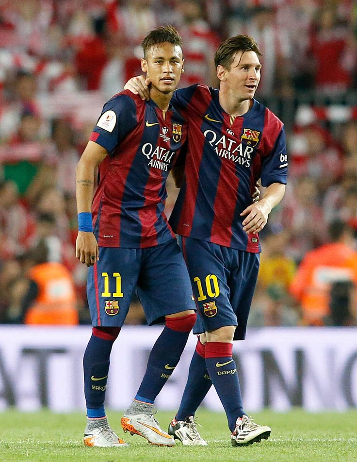 two soccer players standing next to each other in front of a crowd on a field