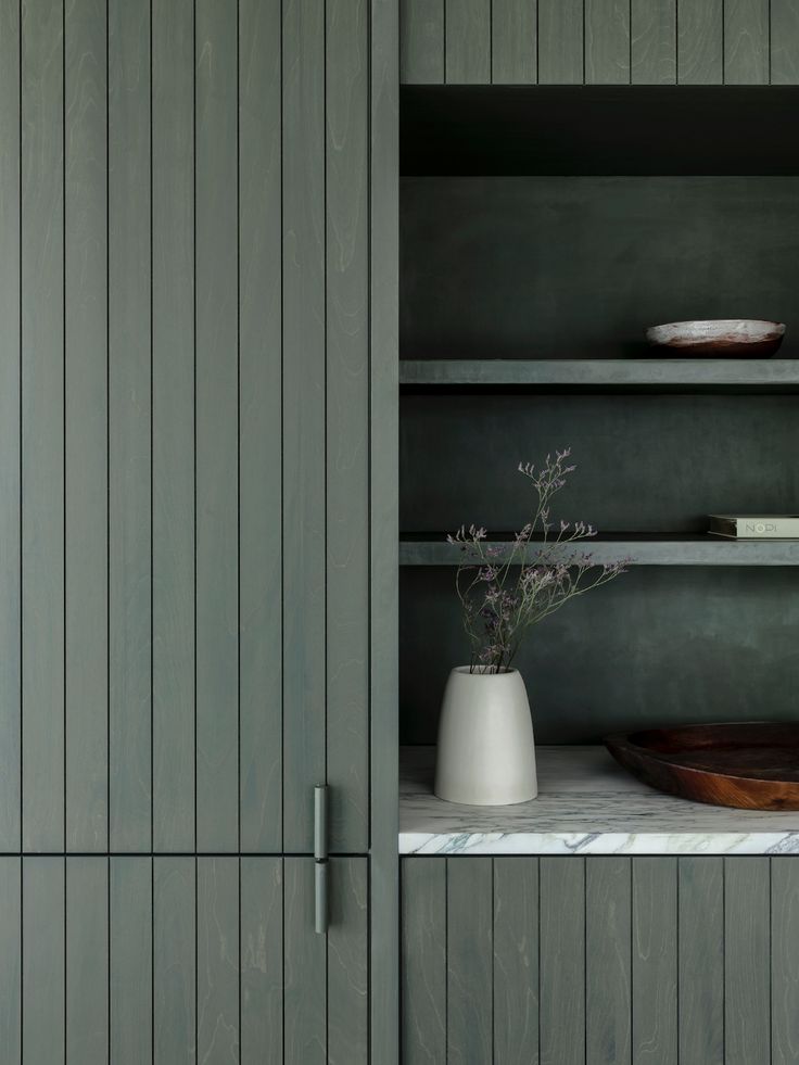 a vase with flowers in it sitting on a shelf next to some bookshelves