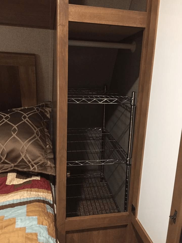 a bedroom with a bed and shelves in the corner next to a door that has a pillow on it