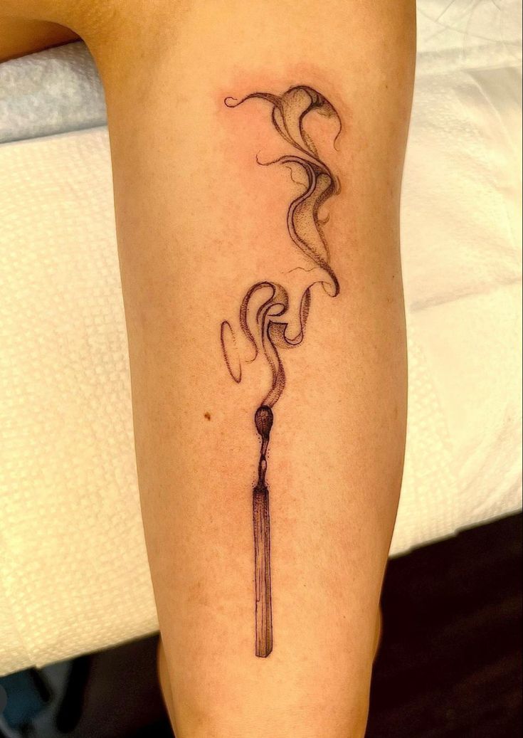 Tattoo of a half burnt match with smoke rising from it in a ribbon style placed on a person��’s lower leg Two Matches Burning Tattoo, Survive Tattoo Symbols, Burning Match Tattoo Design, Burning Paper Tattoo, Burned Match Tattoo, Matchstick Tattoo Meaning, Smokey Match Tattoo, Burnt Out Match Tattoo, Matchstick Tattoo Design