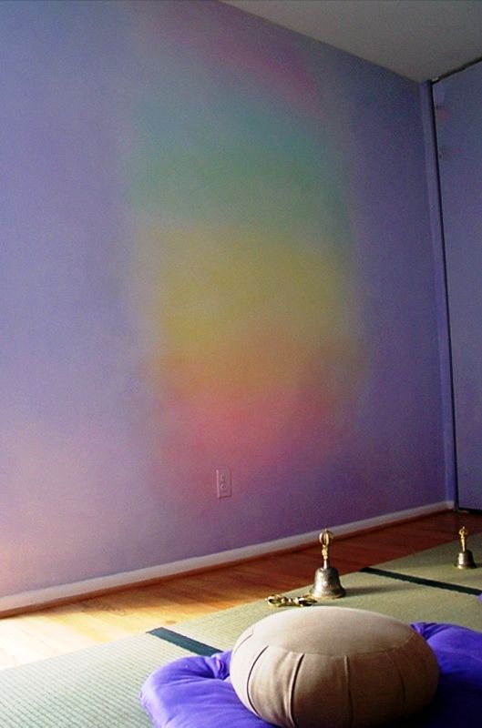 an empty room with a yoga mat on the floor and a rainbow painted wall behind it