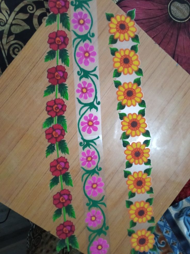 some flowers and leaves are painted on the side of a wooden table with an umbrella in the background