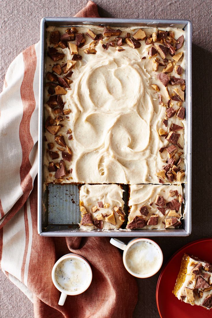 a pan filled with cake next to two cups of coffee