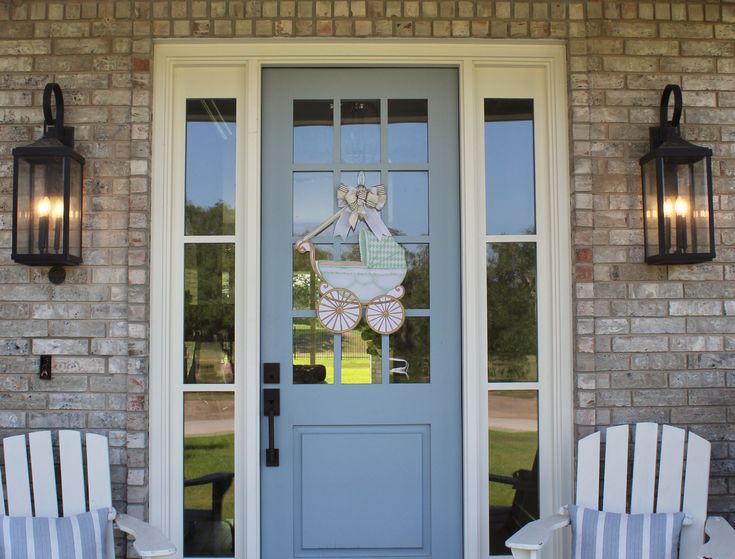 two white chairs sitting in front of a blue door with an angel decoration on it