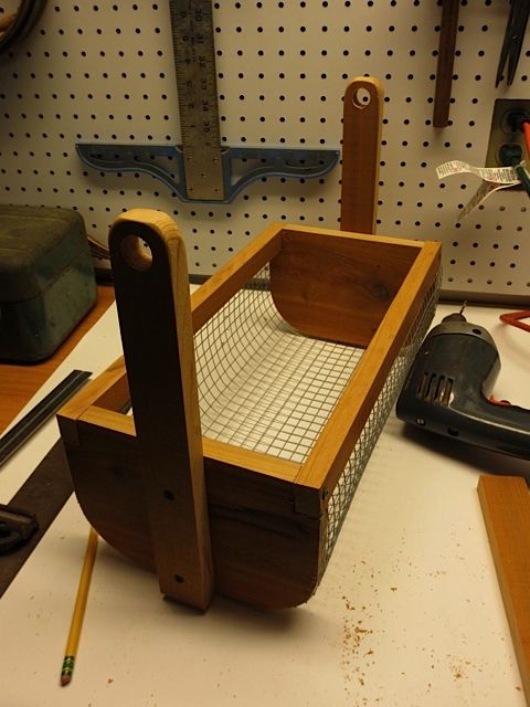 a wooden basket sitting on top of a table next to a pair of pencils