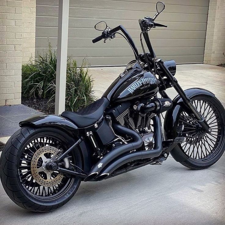 a black motorcycle is parked in front of a garage with its wheels turned to the side