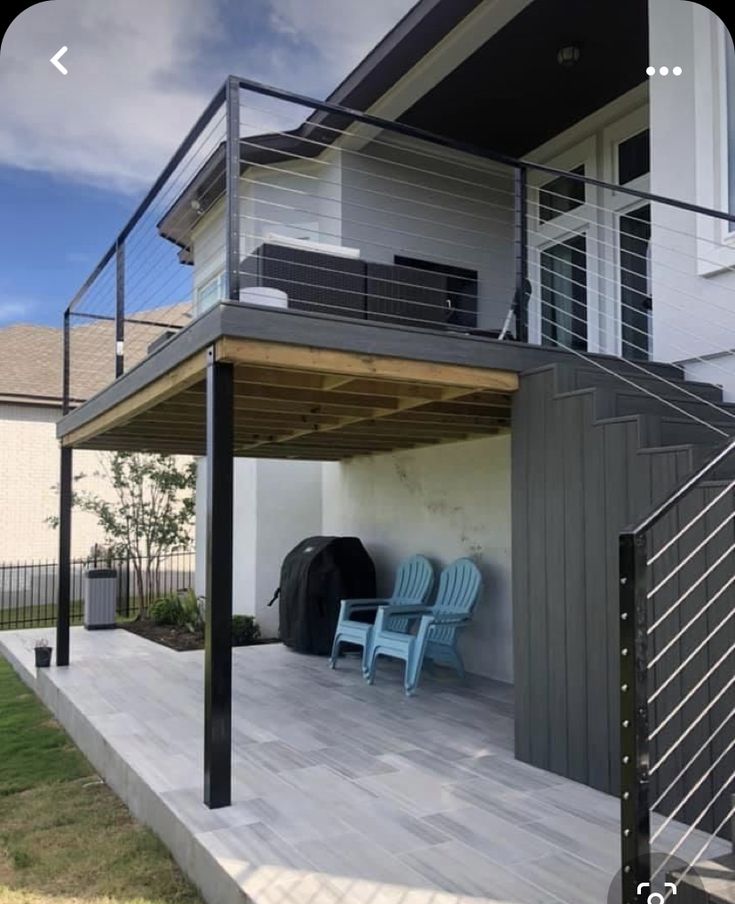 two chairs are sitting on the back porch under an awning that is attached to a house