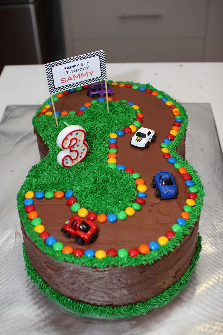 a birthday cake decorated with cars and grass