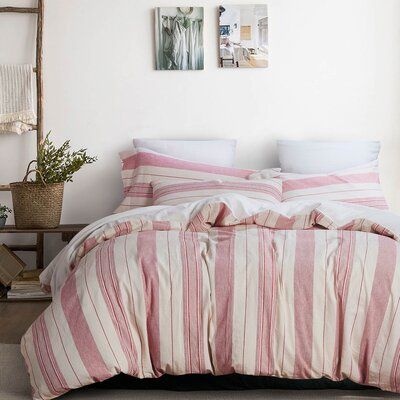 a bed with pink and white striped bedspread next to two pictures on the wall